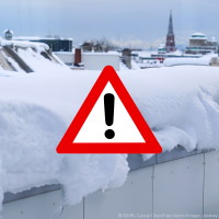 Schnee auf Gebäudedächern rund um das Bauministerium in München. In der Mitte des Bildes ist eine Grafik des Schildes "Warnung vor einer Gefahrenstelle" zu sehen.