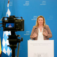 Staatsministerin Kerstin Schreyer zieht nach einem Jahr als Bau- und Verkehrsministerin bei einer Pressekonferenz Bilanz. Sie steht dabei an einem Rednerpult, im Vordergrund ist eine Kamera zu sehen.