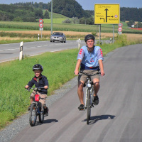 Vater und Sohn radeln auf einem neuen Radweg an der B12